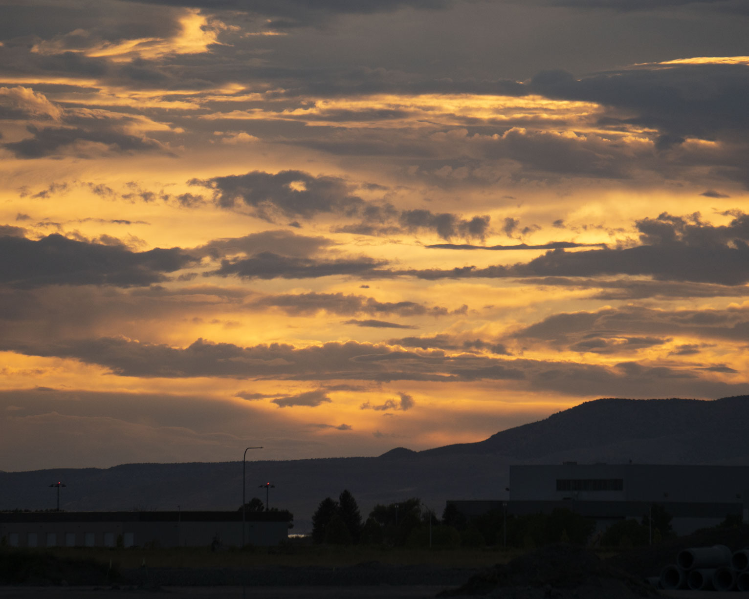 A mix of yellow lit and gry clouds above the airport